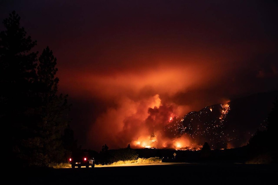 A motorist watches from a pullout on the Trans-Canada Highway as a wildfire burns on the side of a mountain in Lytton, B.C., Thursday, July 1, 2021. THE CANADIAN PRESS/Darryl Dyck