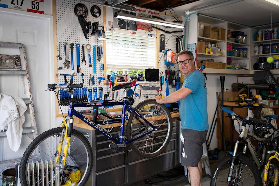 Steve Nicklen, one of the individuals who supports migrant farm workers, repairing bikes at his home in Maple Ridge. (Special to The News)