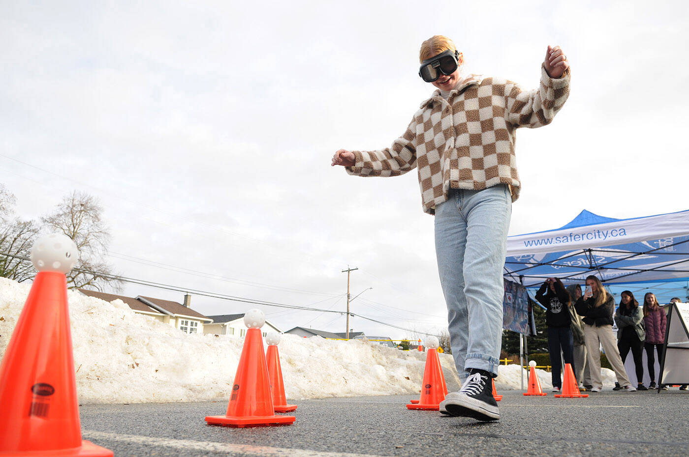 Avery Langbroek, a Grade 10 Sardis Secondary School student, wears impaired goggles while trying to weave through cones without knocking over the wiffle balls on top. MADD launched its six-week impaired driving campaign on Friday, Dec. 9, 2022 at the school in Chilliwack. (Jenna Hauck/ Chilliwack Progress)
