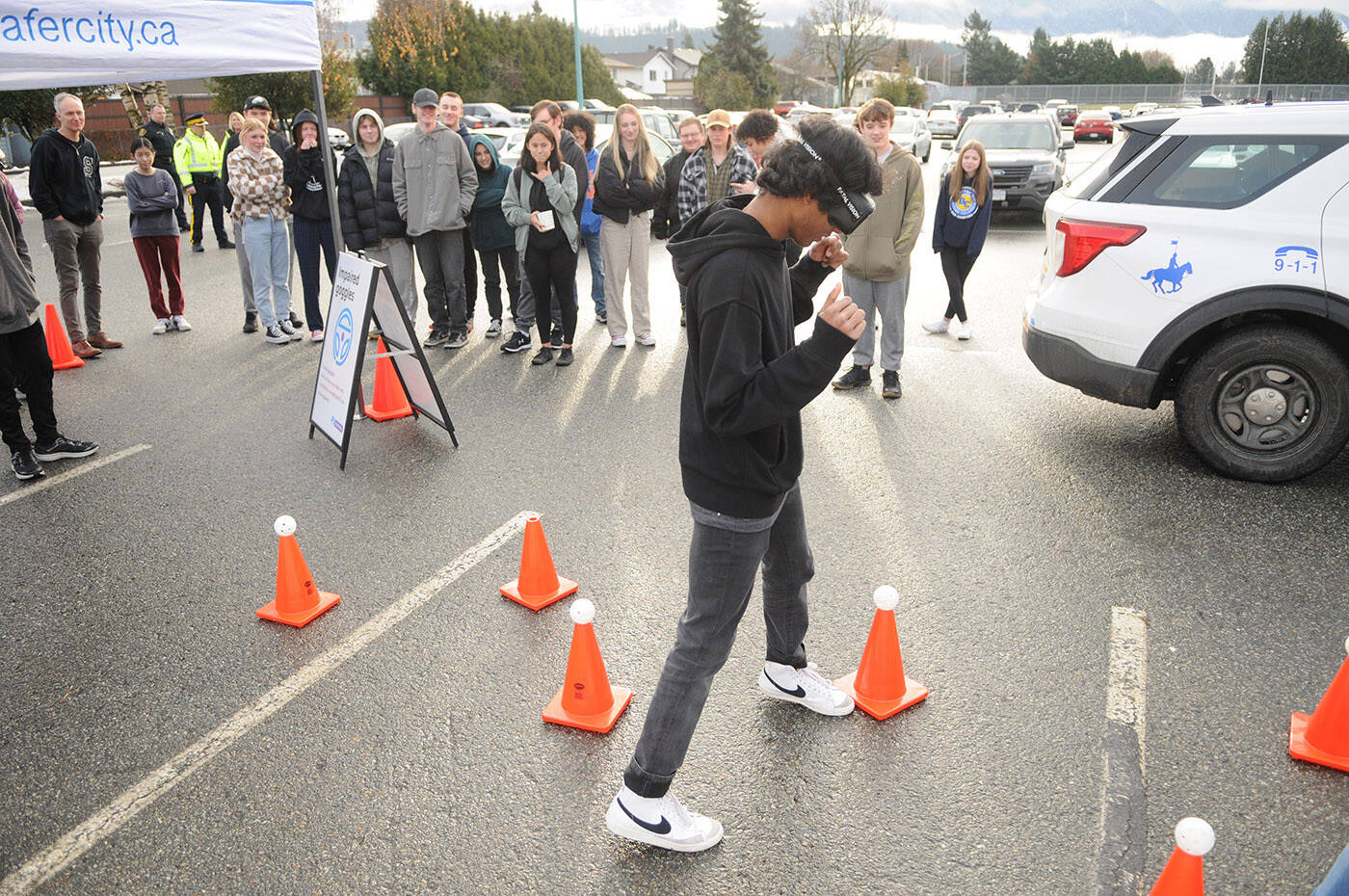 Vinu Weligalle, a Grade 10 Sardis Secondary School student, wears impaired goggles while trying to weave through cones without knocking over the wiffle balls on top. MADD launched its six-week impaired driving campaign on Friday, Dec. 9, 2022 at the school in Chilliwack. (Jenna Hauck/ Chilliwack Progress)