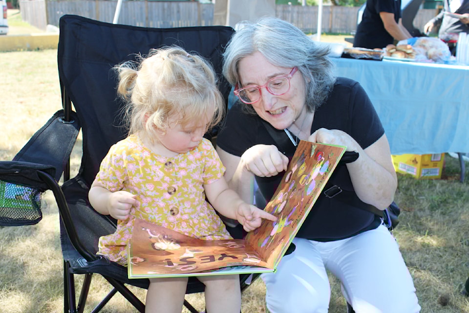 Sue Alvarez of Work BC, who networks with Literacy Alberni, has a look at a book with two-year-old Emersyn Morran.