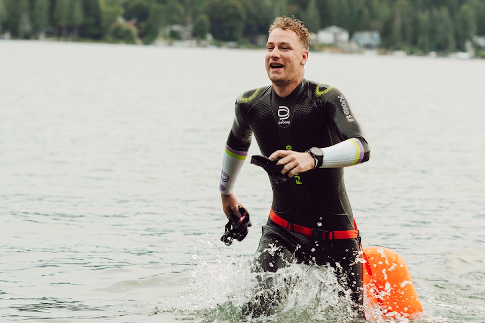 Isaac Ward runs out of the water and up the beach at Sproat Lake Provincial Park after swimming the length of the lake in 12:53 hours on July 26, 2024. (Ezra Tsai Photography)