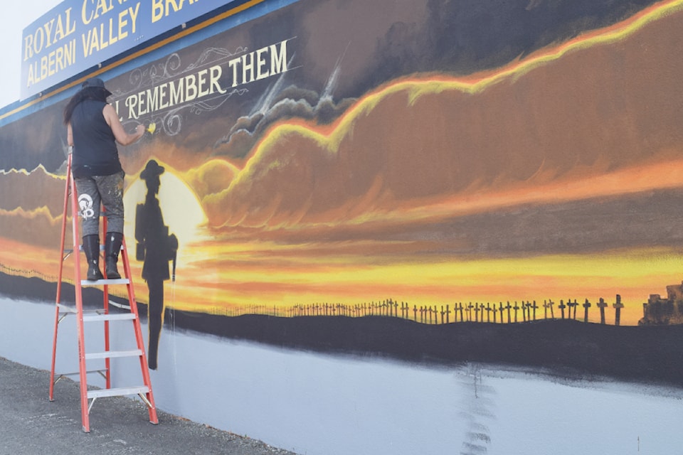 Kelly Everill paints a mural outside of the Royal Canadian Legion Branch 293 building at Victoria Quay on Wednesday, July 24.