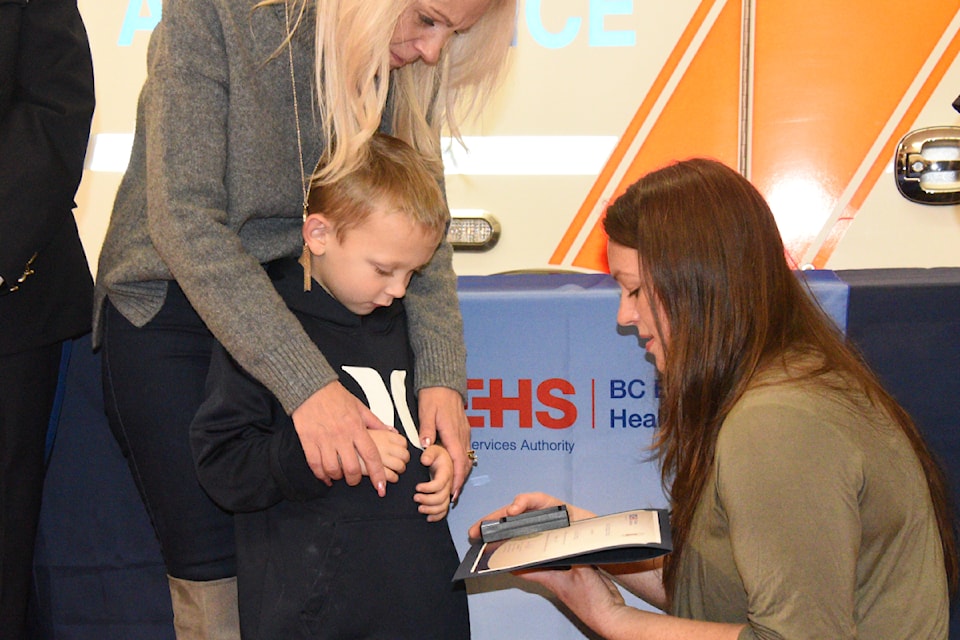 Lisa McFarlane shows her Good Samaritan medal to Jaxson and his mother, Carol Anne Philiips. McFarlane saved Jaxson from choking on a piece of bread. 