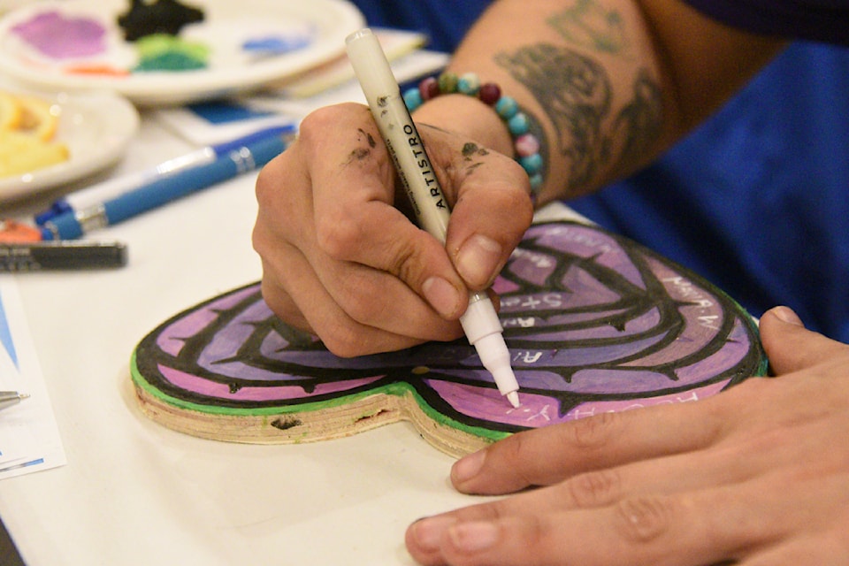 A worker at one of the information tables that were part of International Overdose Awareness Day events in Port Alberni pens heartfelt messages on a wooden heart.