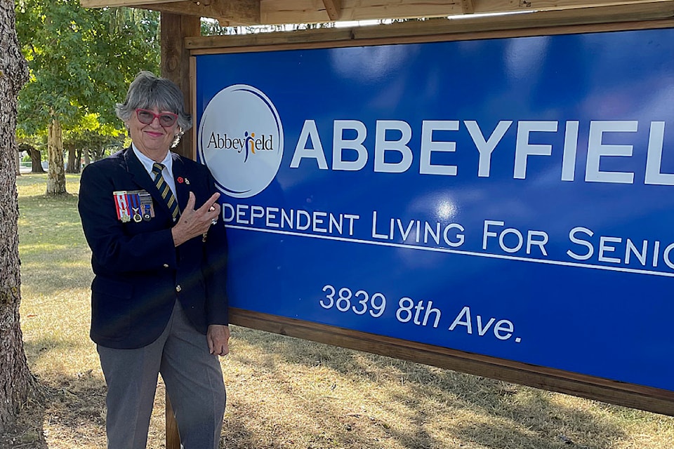 Sandi Paterson, a board member of Abbeyfield House, stands by the newly-built sign on the property's east lawn. 