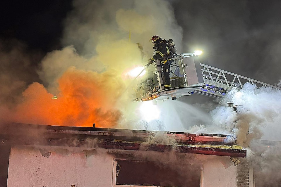 A firefighter on an aerial ladder from Port Alberni Fire Dept. tackles some hard-to-reach areas of a house fire in the 2500-block of 16th Avenue, early Saturday, Aug. 2, 2025. (PAFD PHOTO)
