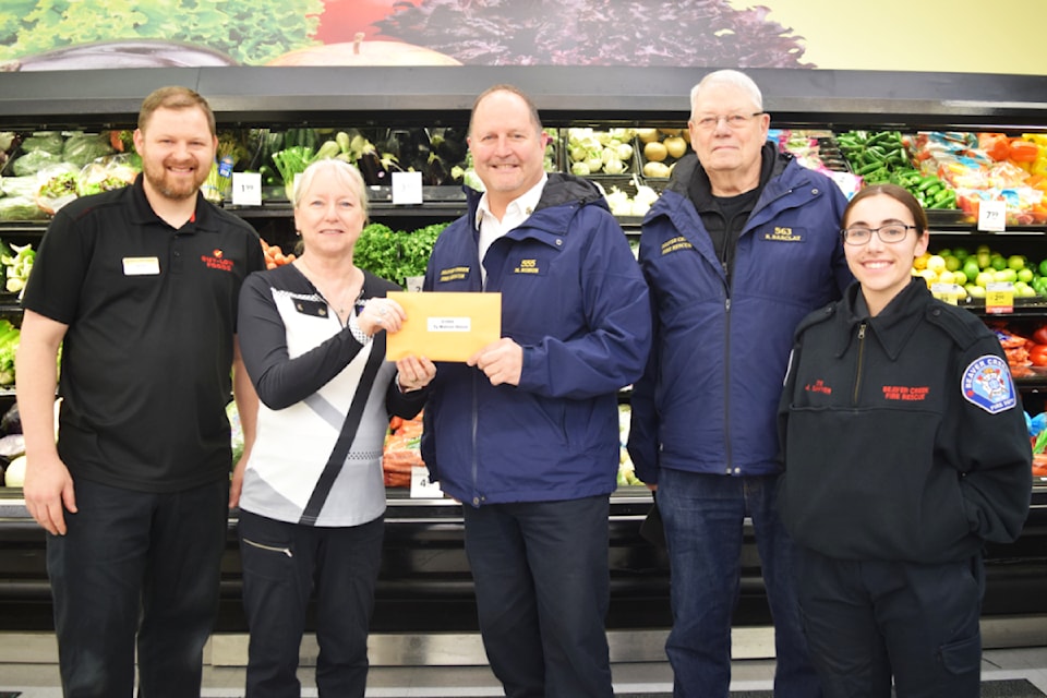 Margaret Vatamaniuck, the executive director for the Alberni Valley Hospice Society, receives a $1,000 donation from the Beaver Creek Volunteer Fire Department and Buy-Low Foods.