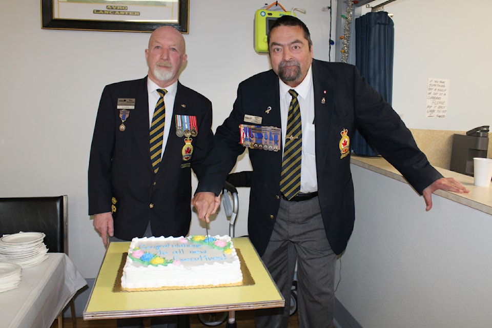 Legion president Roy Buchanan and Achim Sen, the Central Vancouver Island Zone Commander, share the cutting of the cake. 