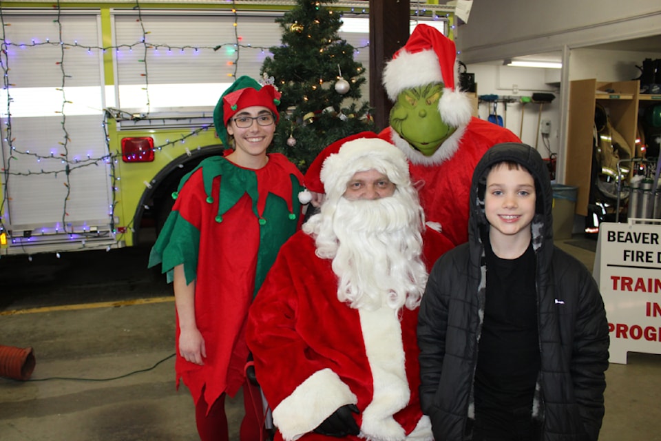 Santa, an elf and the Grinch pose for a photo with Liam Dutchak, 9
