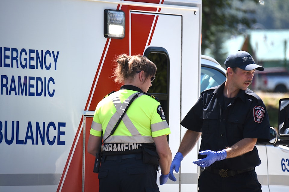 A member of the Port Alberni Fire Department, right, responds to a call about a person down on a sidewalk at Harbour Quay in July 2024. Firefighters and paramedics with BC EHS both responded. 