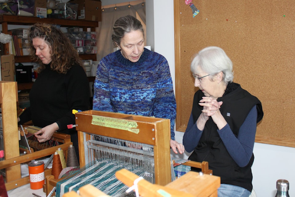 Cathy Bagley the president of the guild, shows Linda Phillips some of the finer points of weaving. 