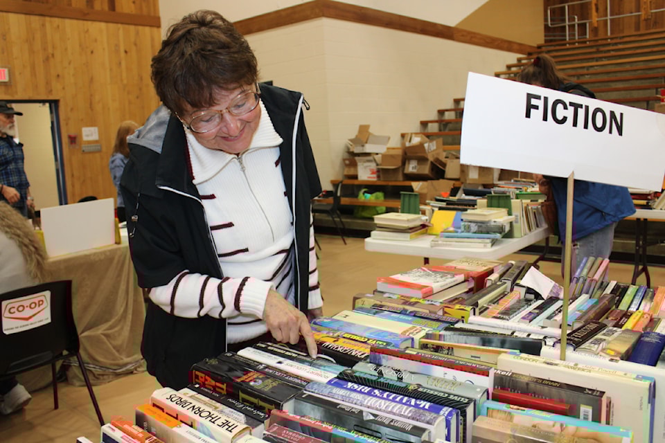 Marta Williamson checks out the titles to find the perfect book to take home from the annual Community Arts Council of the Alberni Valley sale on May 10, 2025. (SONJA DRINKWATER/ Alberni Valley News)