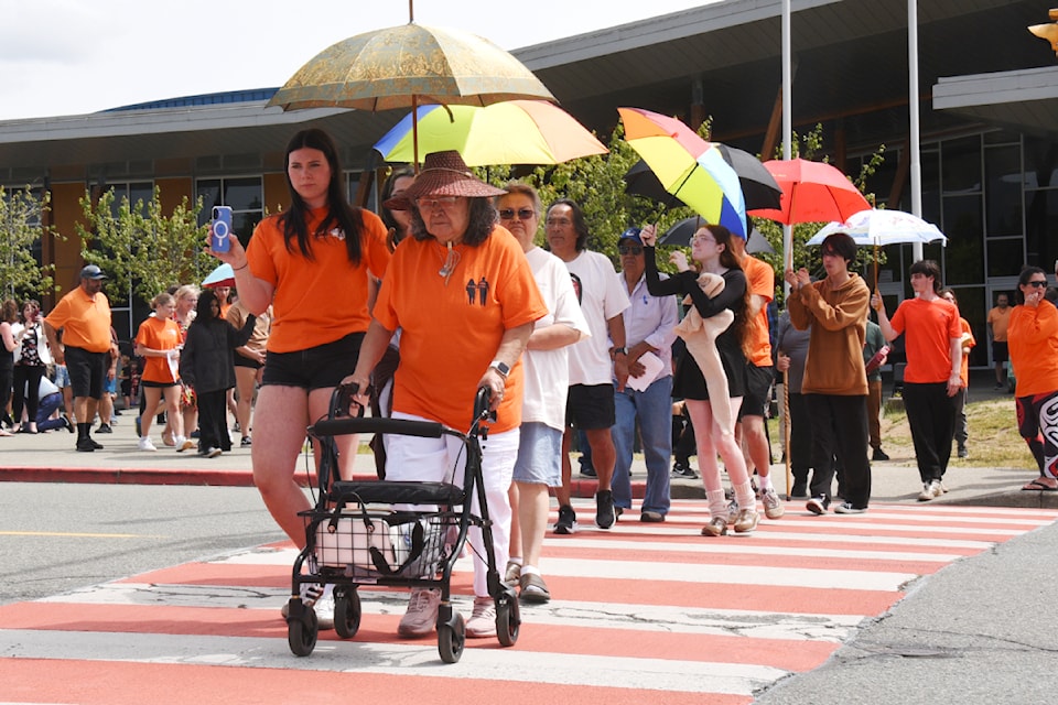 Students from Alberni District Secondary School accompany residential school survivors across the new orange crosswalk in front of the high school on Wednesday, June 11, 2025. The crosswalk, banners and posts are part of a Truth and Reconciliation project from the Social Justice classes of 2024-25. (SUSIE QUINN/ Alberni Valley News)