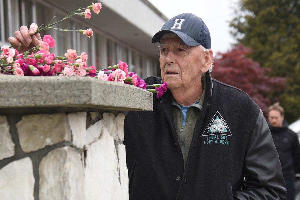 Former Port Alberni mayor and longtime mill worker and union member Ken McRae places a carnation on the memorial for the Day of Mourning, honouring those who lost their lives at work, April 28, 2025. (SUSIE QUINN/ Alberni Valley News)