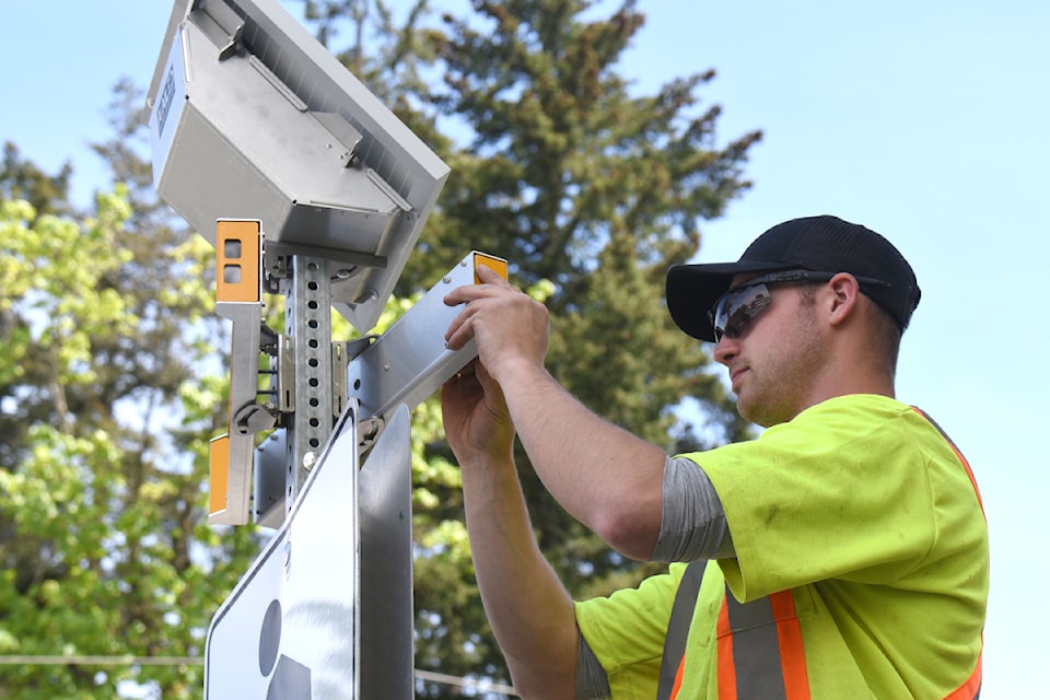 Riley Shiner of Bailey Electric installs a light cover on a pedestrian-activated crosswalk light at Gertrude Street and Pemberton Road in Port Alberni, May 5, 2025. (SUSIE QUINN/ Alberni Valley News)