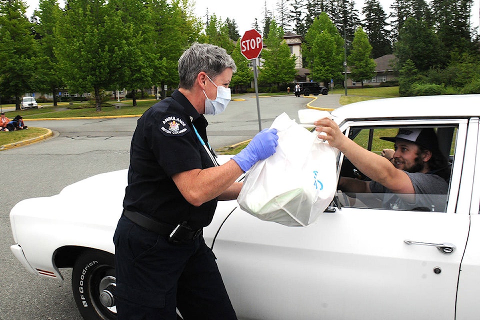 Deb Roberts from B.C. Ambulance Service accepts a donation of food from a participant in the Cruise for Care on Friday, June 19, 2020. Dozens of cars lined up in the parking lot of the Alberni Athletic Hall, most of them with food donations. (SUSAN QUINN/ Alberni Valley News)