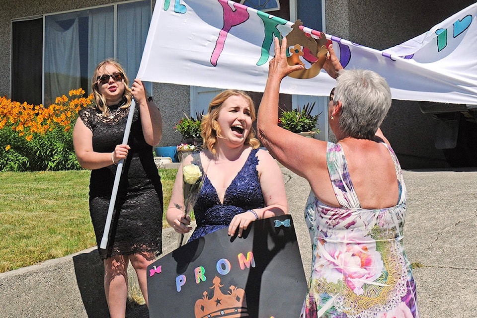 A member of the Young Life Prom on Wheels team prepares to crown ADSS Class of 2020 graduate Morgan Schoen as ‘prom queen’ during a drive-by grad party in Port Alberni on Sunday, June 28, 2020. Twenty grads signed up to have the mini-party come to their homes. (SUSAN QUINN/ Alberni Valley News)