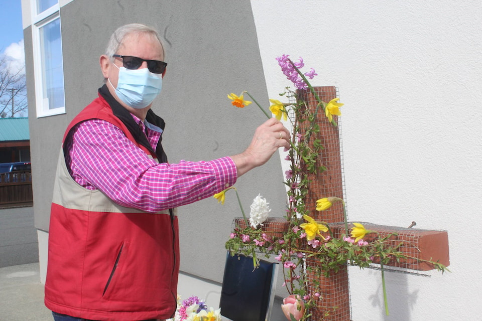 Bob Watson adds a flower to the cross on Sunday at the Alberni Valley Christian Reformed Church on Roger Street. (SONJA DRINKWATER / SPECIAL TO THE NEWS)