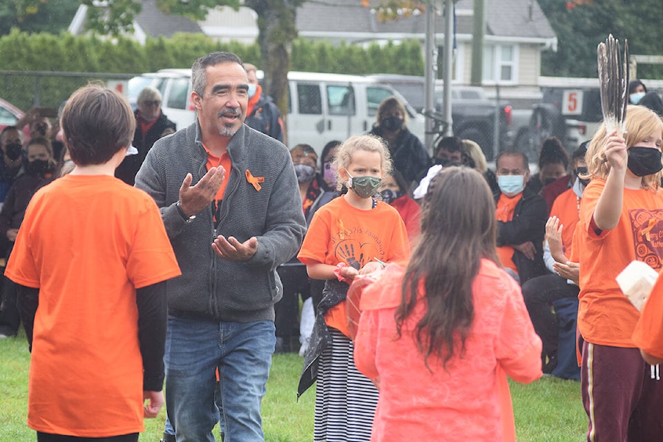 Nuu-chah-nulth Education Worker Aaron Watts leads Tsuma-as Elementary School students as they perform a Nuu-chah-nulth celebration song during the unveiling of Tsuma-as Elementary School’s new name. (ELENA RARDON / ALBERNI VALLEY NEWS)