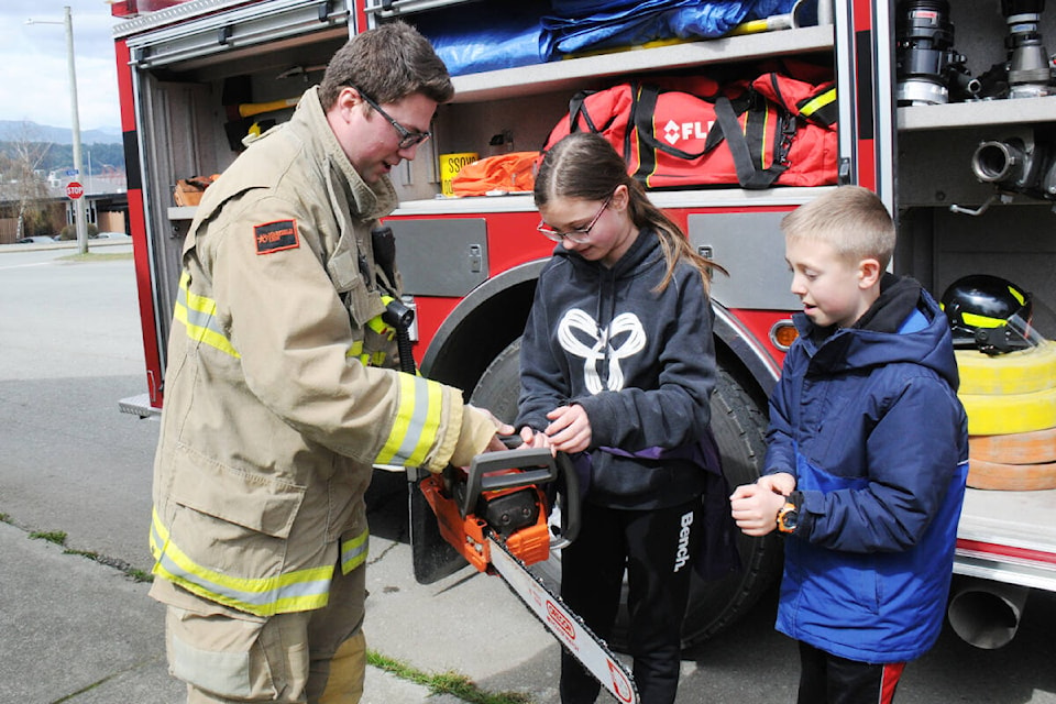 HIKING TO HIGH GROUND Cherry Creek VFD firefighter Darren Francoeur, left, instructs Neveah McDougall, centre, and Brenan Little from Maquinna Elementary School on how to safely hold a chainsaw during a Hike to High Ground event April 12, 2022 for Tsunami Preparedness Week. See more from this event on page A5. (SUSAN QUINN/ Alberni Valley News)