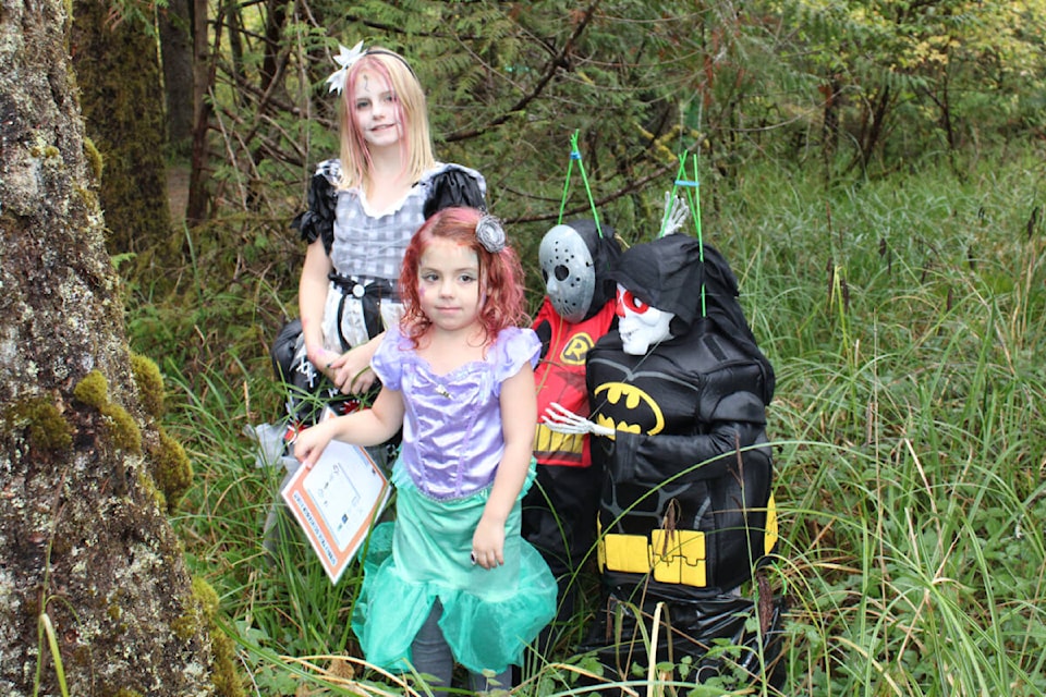 Sisters Brooklin Albaya (age eight) and Maci (age four) pose with a few of the scary characters that were in the haunted forest at Beaver Creek Community Hall. (SONJA DRINKWATER / ALBERNI VALLEY NEWS)