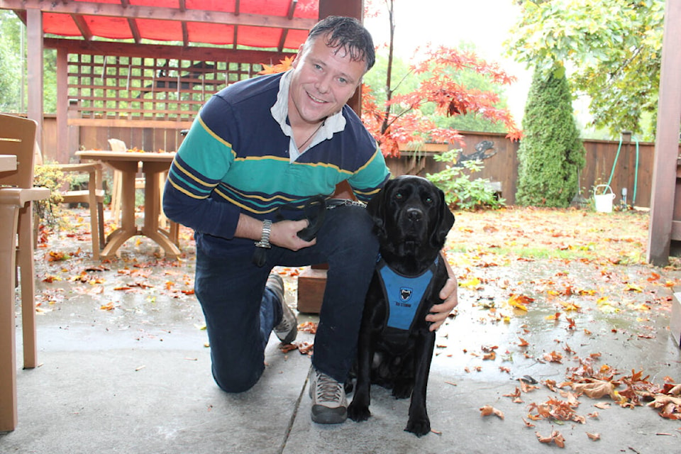 Shawn Standley crouches with his support dog, Jo Jo, in their Port Alberni backyard. (SONJA DRINKWATER/ Special to the AV News)