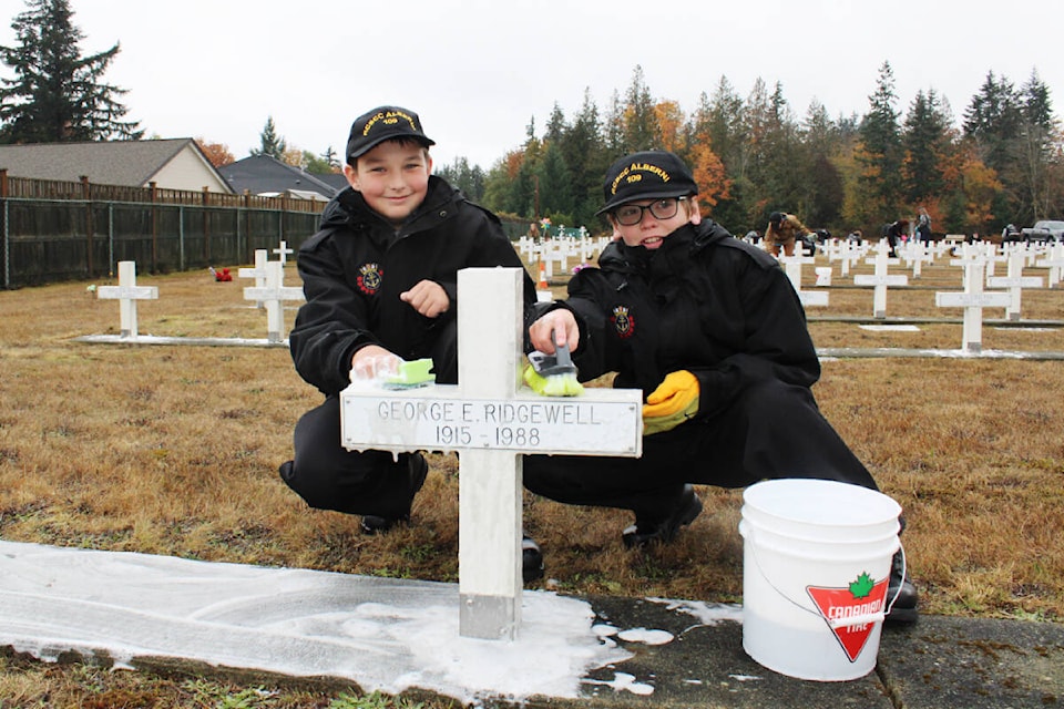 Ordinary Cadets Richard Bezanson, left, and Izaiah Geddes from the Royal Canadian Sea Cadet Corps Port Alberni scrub the cross for George Ridgewell in the Field of Honour at Greenwood Cemetery in Port Alberni on Sunday, Nov. 6, 2022. Cadets joined members of the Pacific Commandos Motorcycles in cleaning the area. (SONJA DRINKWATER/ Special to the AV News)
