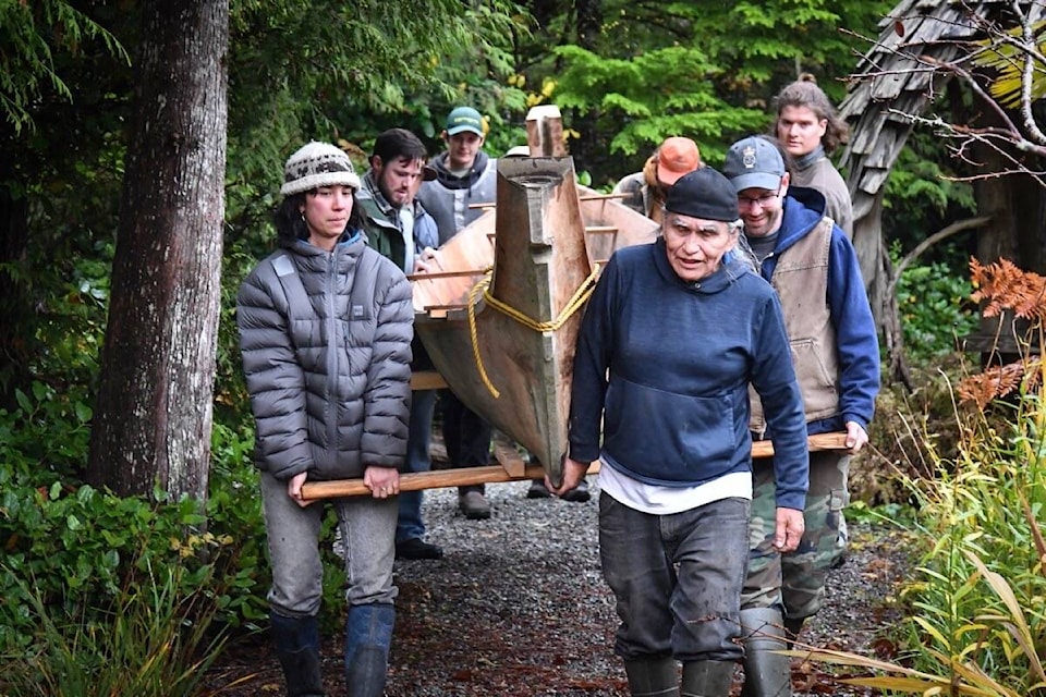 Carl Martin Sr. (front right), carries the canoe back to the carving shed with the support of those in attendance after the steaming. It will dry out before being worked on further. (Marcie Callewaert photos)