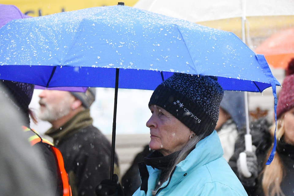Walkers participating in the Coldest Night of the Year walk in Uptown Port Alberni stand in the wet snow as they listen to speakers talk briefly about the reason behind the walk. (SUSAN QUINN/ Alberni Valley News)