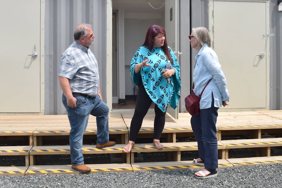 Cyndi Stevens, centre, executive director for the Port Alberni Friendship Centre, stands in front of the newly constructed washroom faciltiies at Walyaquil Tiny Home Village with Courtenay-Alberni MP Gord Johns and Carolyn Bennett, the Canadian minister of mental health and addictions. (ELENA RARDON / Alberni Valley News)
