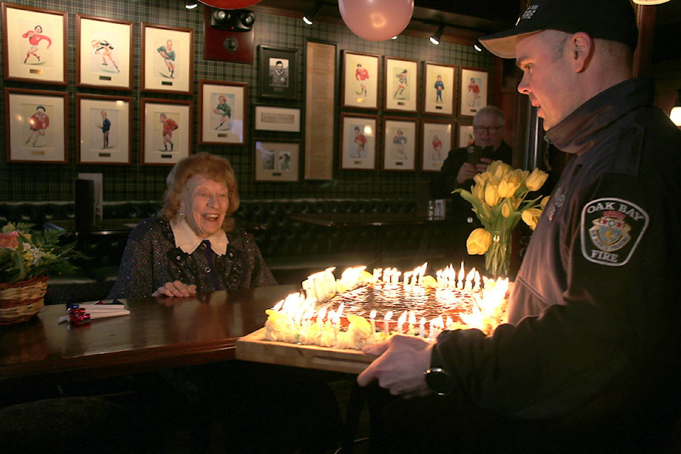 Constance Isherwood is presented a birthday cake with a 100 candles on top by Oak Bay fire fighter Jason Ahokas. (Kendra Crighton/News Staff)