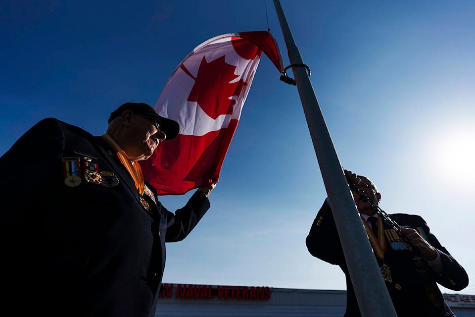 Korean War veterans Andy Barber, left, and Ron Kirk, raise the Canadian flag at the Halton Naval Veterans Association Burlington, Ont. on Friday November 6, 2020. Barber and Kirk served as in the navy as part of a peacekeeping force immediately following the armistice in July 1953. THE CANADIAN PRESS/Mark Blinch