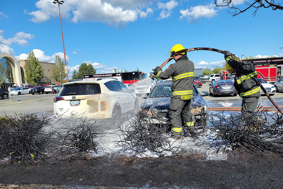 Firefighters soak a scorched stretch of trees in the parking lot of the Willowbrook Mall on Wednesday afternoon. The parking lot fire caused the evacuation of the mall. (Dan Ferguson/Langley Advance Times)