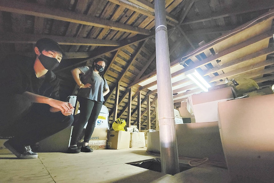 Aldergrove Community Secondary School students Jacky Guyho (left) and Iris Okazaki were sorting through historic artifacts in the attic of the Alder Grove Heritage Society museum at 3190 271 St. on Sunday, March 13. (Dan Ferguson/Langley Advance Times)