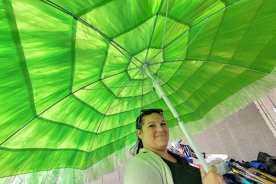 A shopper tried out a parasol at the Penny Pincher and Langley Memorial Hospital Auxiliary anniversary celebrations at the Langley City thrift store on Saturday, July 9. (Dan Ferguson/Langley Advance Times)