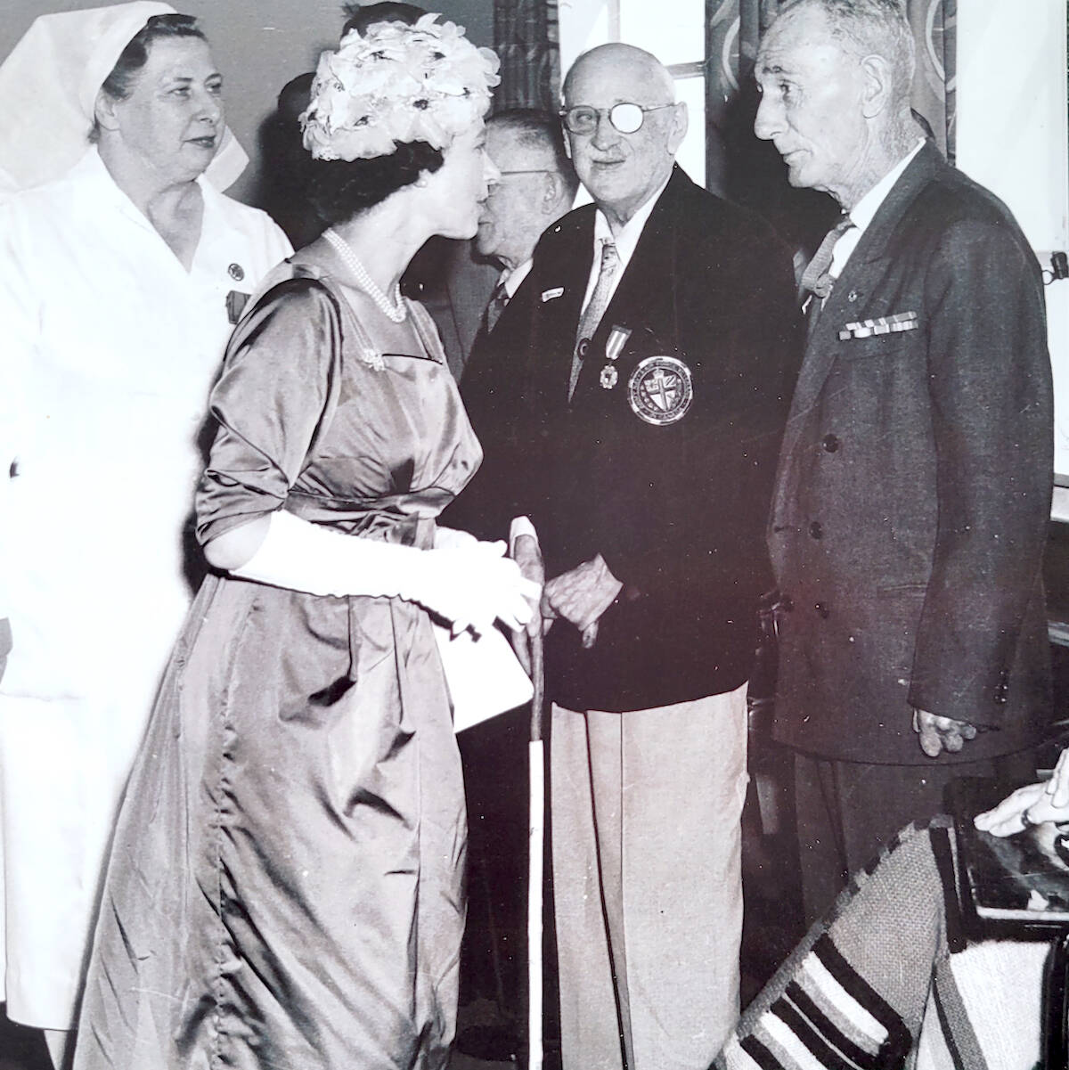 A photo, prized by Royal Canadian Legion Aldergrove Branch member Vivian Lillico, shows Queen Elizabeth speaking with veteran Roland Aldersmith (centre, with cane), Lillicos grandfather, during a visit to a veterans pavilion in a Victoria hospital during a 1959 tour of Canada. (Special to Langley Advance Times)