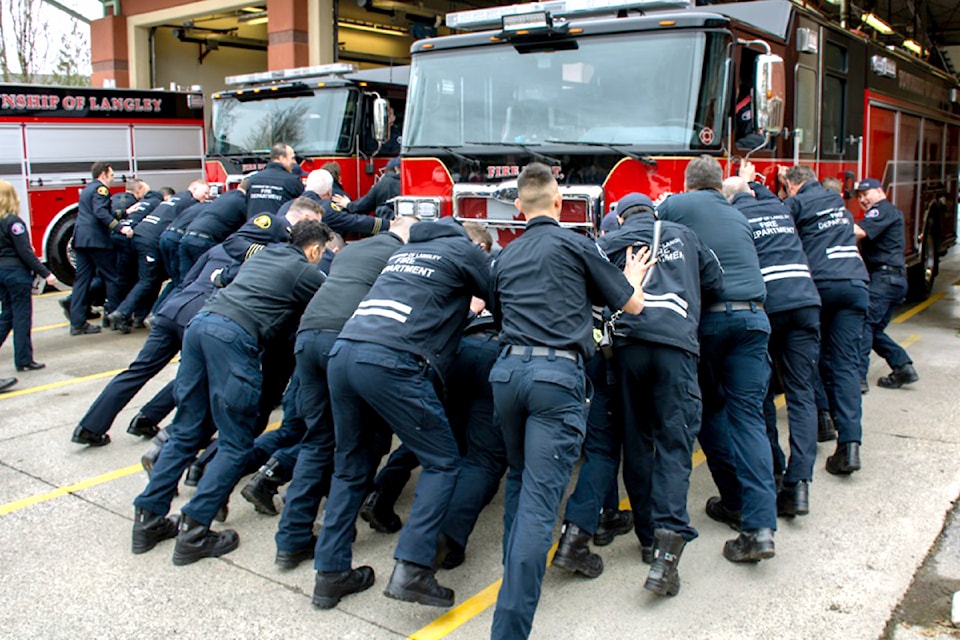  Township firefighters perform the 'push-in' ceremony at the Murrayville fire hall of two new trucks going into service. ( Township/Special to The Star)