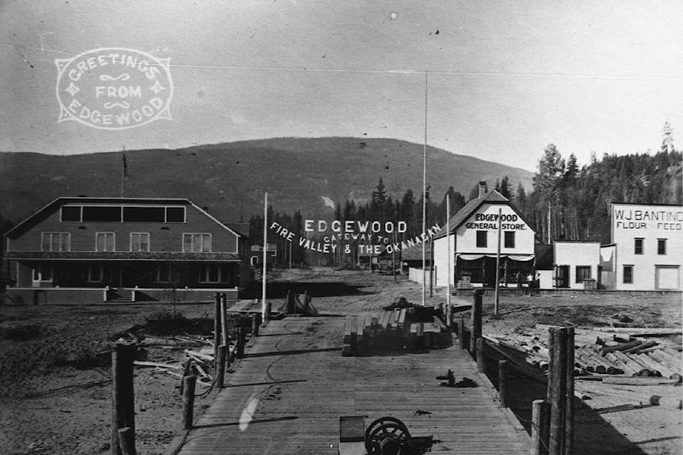 This oversize postcard shows the view looking down the wharf and Inonoaklin Valley Road at Edgewood, 1912-1914. Lake Drive runs through the photo above wharf. The Arrow Lakes Hotel is at left, with W.J. Banting’s new Edgewood General Store to right of the Valley Road and ‘Edgewood - Gateway to Fire Valley & the Okanagan’ sign. A real estate office to right of general store, and Banting’s original store is at far right. Photo/postcard by Hughes Bros. (Photo from Arrow Lakes Society 2014.003.5217 Greetings From Edgewood)
