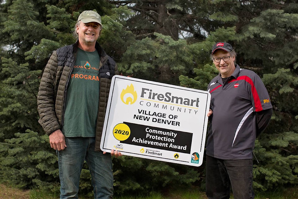 Leonard Casley, mayor of New Denver, accepts the village’s FireSmart Community award from Stephan Martineau, Manager SIFCo. (Contributed)