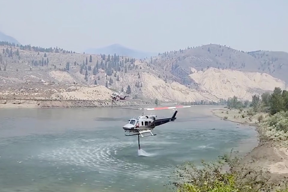 Two helicopters take on water near Spences Bridge in order to tackle the Shetland Creek wildfire.