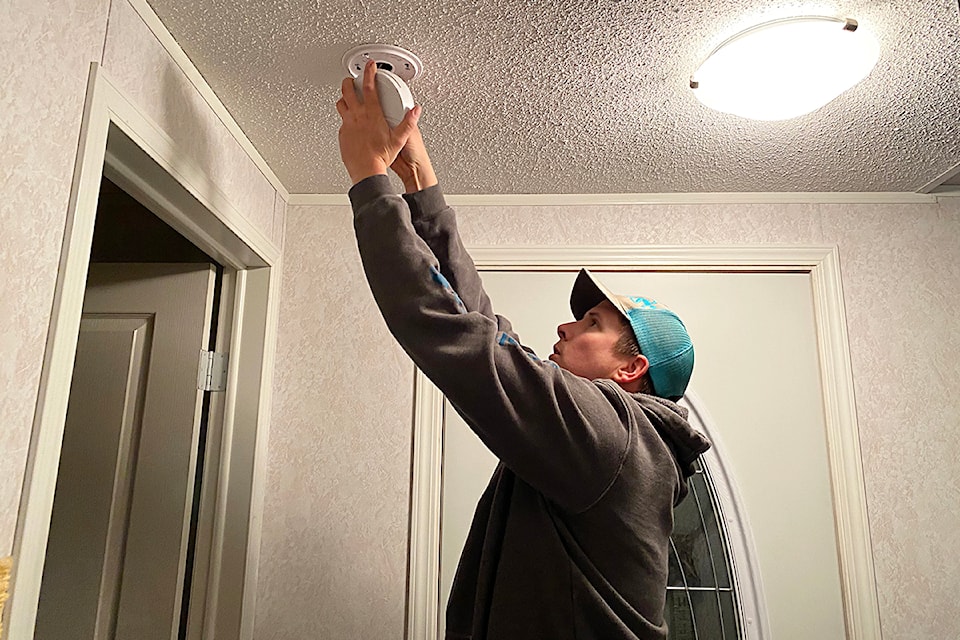 A firefighter with the Blackpool Fire Department in the North Thompson installing a smoke detector in a mobile home park unit.