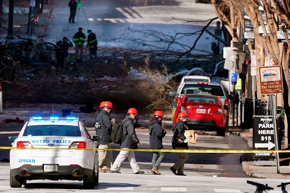 Investigators walk near the scene of an explosion Saturday, Dec. 26, 2020, in Nashville, Tenn. The explosion that shook the largely deserted streets of downtown Nashville early Christmas morning shattered windows, damaged buildings and left several people wounded. Authorities said they believed the blast was intentional. (AP Photo/Mark Humphrey)