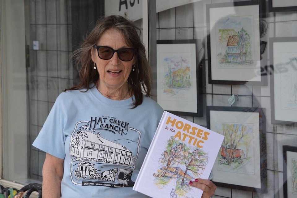 Ashcroft artist Martha Labadie, wearing a T-shirt she designed for Historic Hat Creek Ranch, in front of some of her works on display in the Sidewalk Gallery until the end of the month. (Photo credit: Barbara Roden)