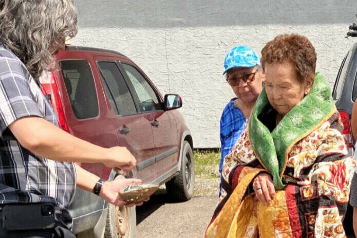 Stemete7uw’i Friendship Centre manager Murray Casey smudges Cathy Harry as part of a blanket ceremony. (Fiona Grisswell photo - 100 Mile Free Press)