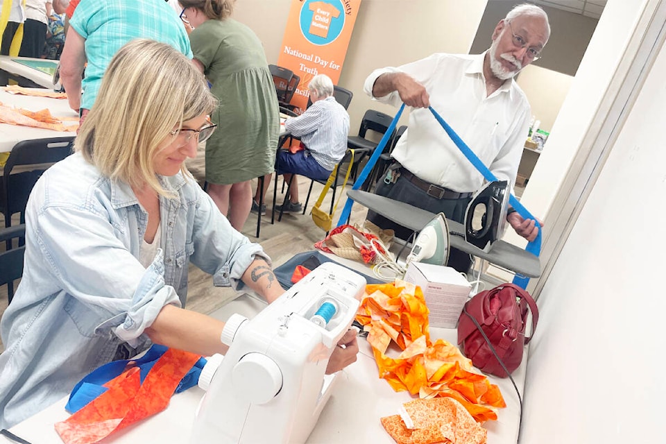 Venta Rutauskas, left, and Mayor Surinderpal Rathor were helping to put the pieces together as part of an Orange Shirt Day special project. (Ruth Lloyd photo - Williams Lake Tribune)