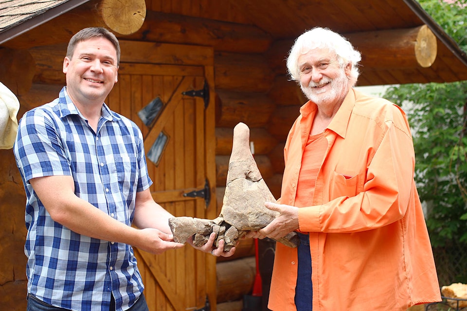 Dr. Caleb Brown, left, and Garry McCue hold the piece of Triceratops horn being donated to the Royal Tyrrell Museum. Note: Image was altered to remove location-identifying information. (Emily Jaycox/Ponoka News)