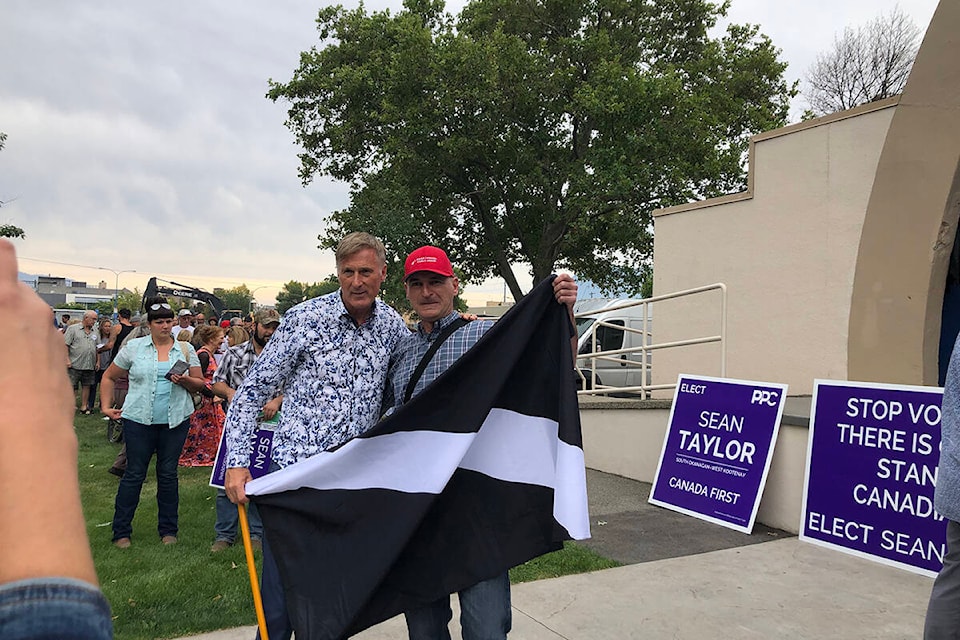 People’s Party of Canada (PPC) leader Maxime Bernier poses for a picture with a man wearing a ‘make Canada great again’ hat and carrying a black and white flag at a rally held at Gryo Park in Penticton Sunday morning. (Monique Tamminga Western News)