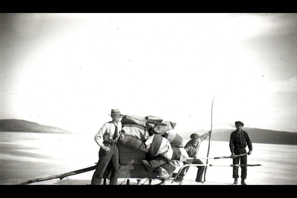 Three men pull a sleigh laden with mail bags across a lake in the Lakes District during the last century. The man on the left is likely Norman Schreiber, Ootsa's pioneer mailman.