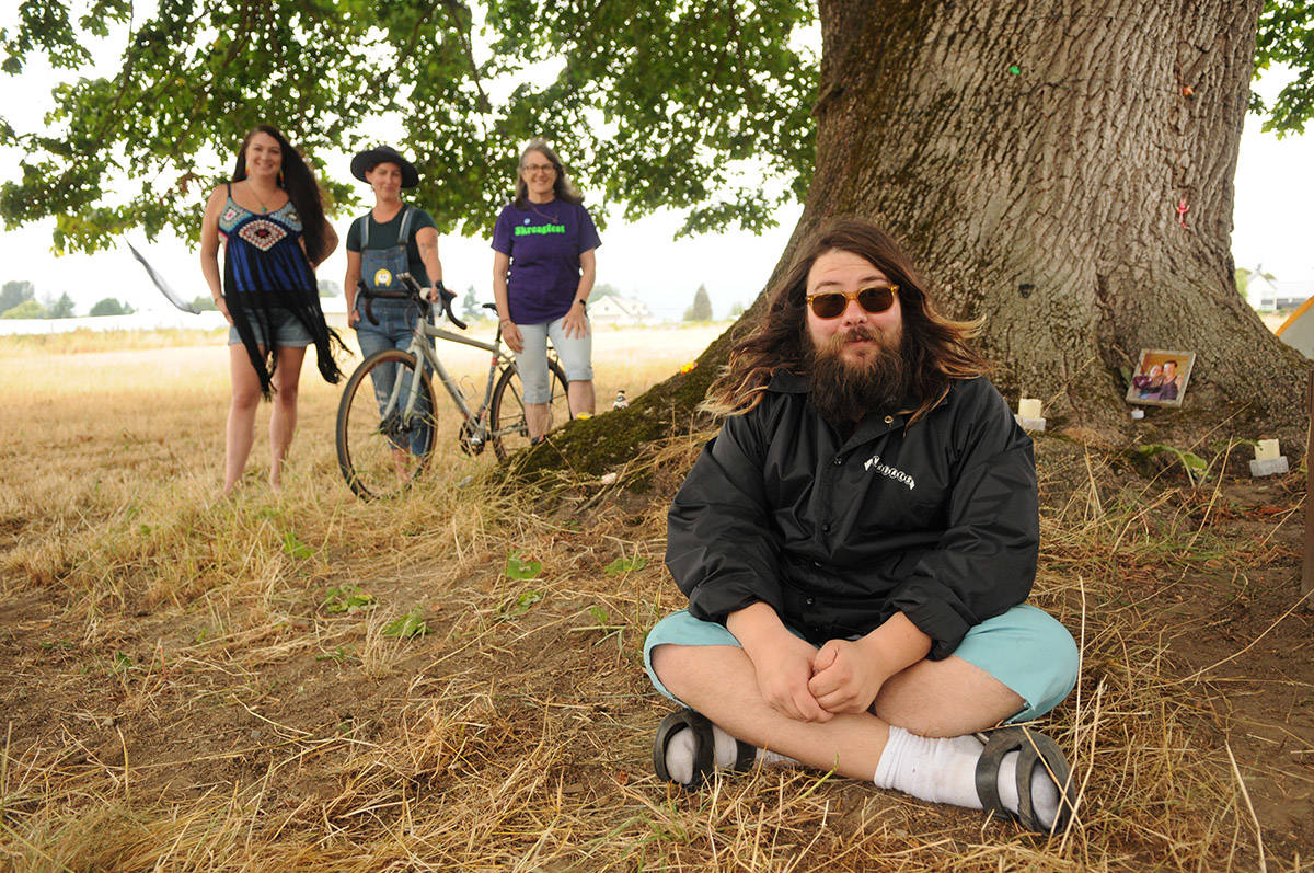 Mark Penner (Sarah Penner聮s husband) sits in front of a tree surrounded with photos of Sarah and other memorabilia during Skreagfest on Saturday, Aug. 21, 2021. Behind him, from left, are Meghan McCusker (friend and nurse), Carla Swope (Team Sarah member who will be doing her own 160-kilometre bike ride in the Tour de Cure), and Sarah聮s aunt Earla Legault. (Jenna Hauck/ Chilliwack Progress)